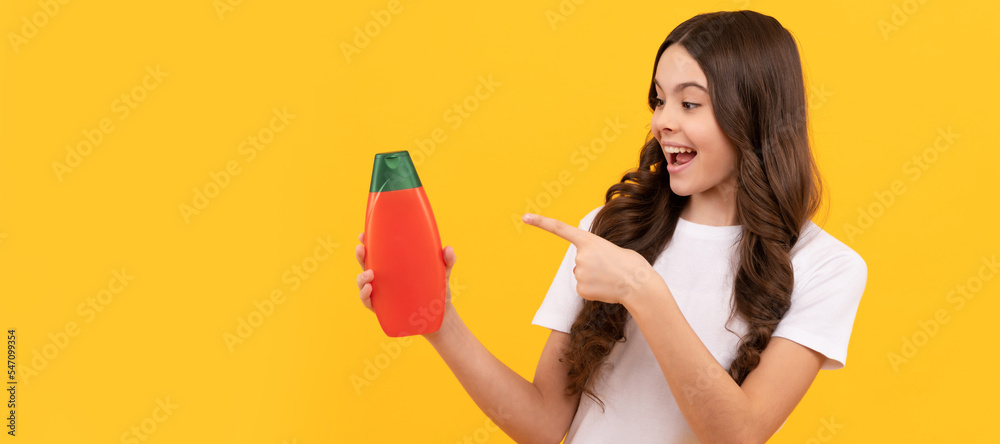 presenting cosmetic product for teen. kid with shower gel. happy girl hold shampoo bottle. Banner of child girl hair care, studio poster header with copy space. presenting cosmetic product for teen. kid with shower gel. happy girl hold shampoo bottle. Banner of child girl hair care, studio poster header with copy space.