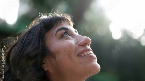 Happy woman standing in nature taking a deep breath closing eyes in contemplation. Meditative hispanic latina girl opening eyes to sky