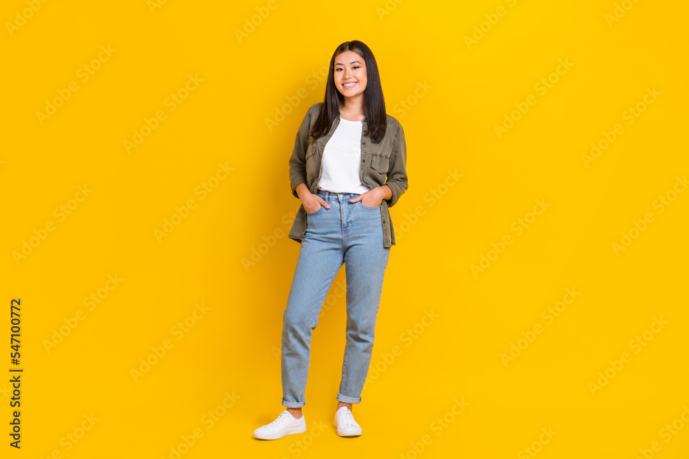 Full body length photo of young smiling cute korean business lady it company owner casual outfit hands pockets isolated on yellow color background Full body length photo of young smiling cute korean business lady it company owner casual outfit hands pockets isolated on yellow color background