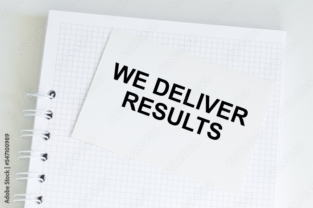 WE DELIVER RESULTS Text written on the notepad WE DELIVER RESULTS Text written on the notepad
