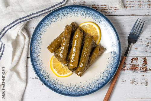 Stuffed leaves with olive oil on a white wooden background. Mediterranean cuisine delicacies. Local name zeytinyagli yaprak sarma. Top view photo