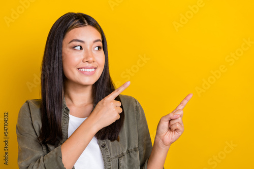 Closeup photo of cute japanese girl wear khaki shirt fingers direct look empty space showing new useful service isolated on yellow color background