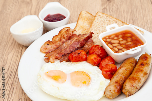 English breakfast set with fried egg, sausage, bacon, grilled tomato, baked bean and toast