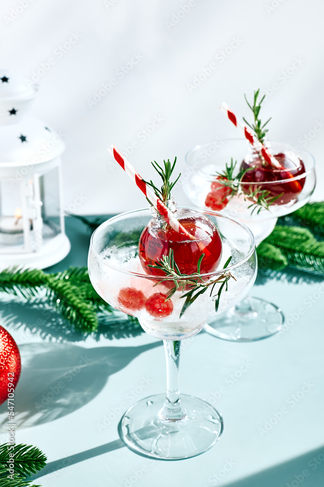 Christmas refreshment drink mimosa, punch or cranberry margarita cocktail serving in christmas ornaments and martini drinking glasses. Delicious icy drink idea for christmas and winter holiday party.