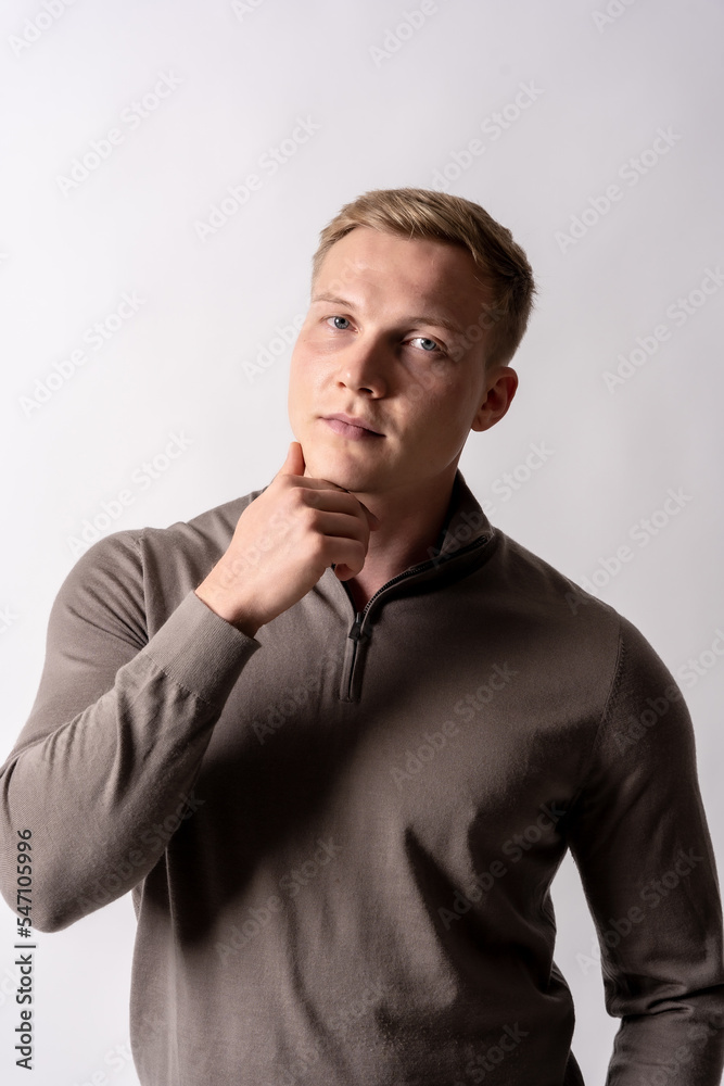 Portrait of a blond german model with a brown sweater on a white background, looking at the camera Portrait of a blond german model with a brown sweater on a white background, looking at the camera