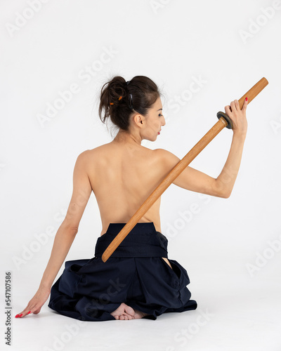 Aikido master woman in traditional samurai hakama kimono with black belt with wooden sword bokken, katana on white background. Healthy lifestyle and sports concept.