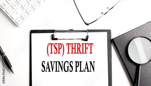 TSP THRIFT SAVINGS PLAN text written on paper clipboard with office tools photo