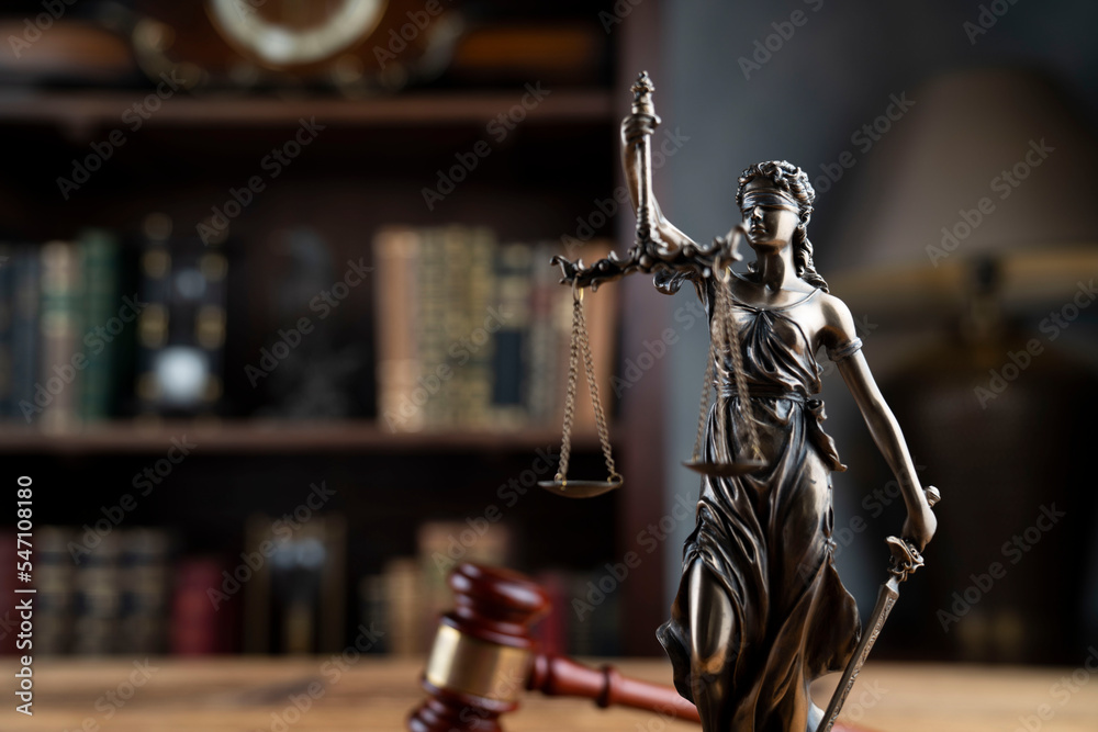 Lawyer office. Judge’s gavel, Themis sculpture and legal books in the bookshelf. Lawyer office. Judge’s gavel, Themis sculpture and legal books in the bookshelf.
