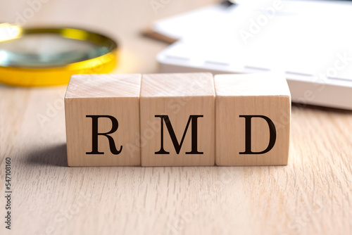 RMD on wooden cubes with magnifier and calculator, financial concept background