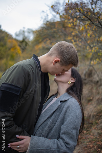 Couple lovers young hugging and kissing outside in an autumn park. Love, youth, happiness, relationship, couple, dating, love couple, dating app, lonely heart, broken heart, valentines day concept 