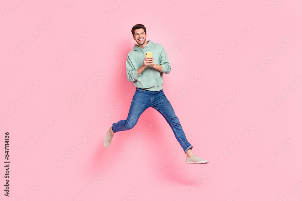 Full length photo of overjoyed positive man wear stylish khaki clothes rejoice new cool device telephone isolated on pink color background