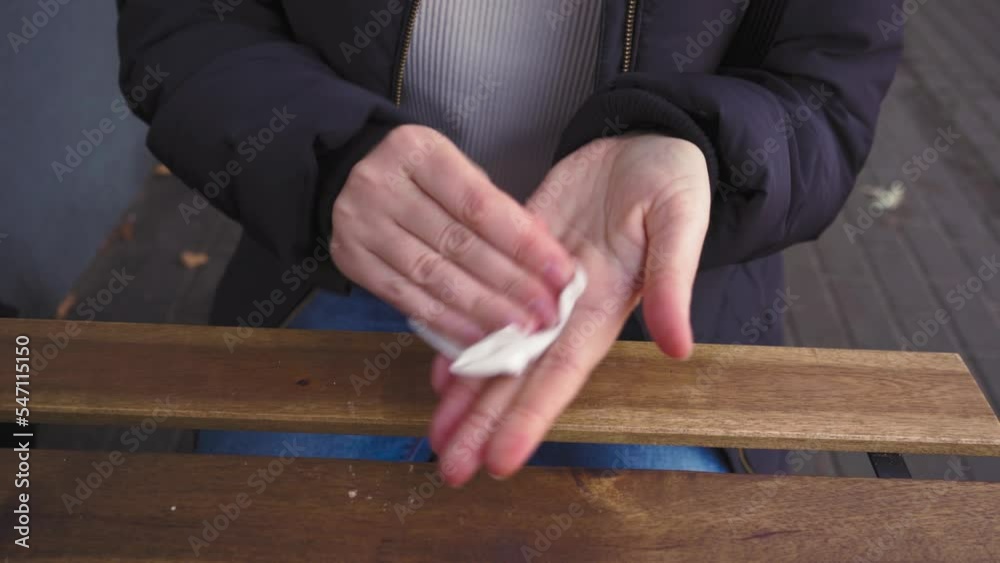 A Woman Wipes Table and Hands in Cafe with Disposable Napkin, Hygiene Concept, Using Antibacterial Wet Wipes for Cleaning and Disinfection A Woman Wipes Table and Hands in Cafe with Disposable Napkin, Hygiene Concept, Using Antibacterial Wet Wipes for Cleaning and Disinfection
