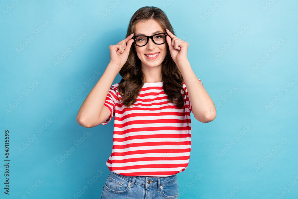 Photo of pretty adorable lady wear striped t-shirt arms spectacles smiling isolated blue color background Photo of pretty adorable lady wear striped t-shirt arms spectacles smiling isolated blue color background