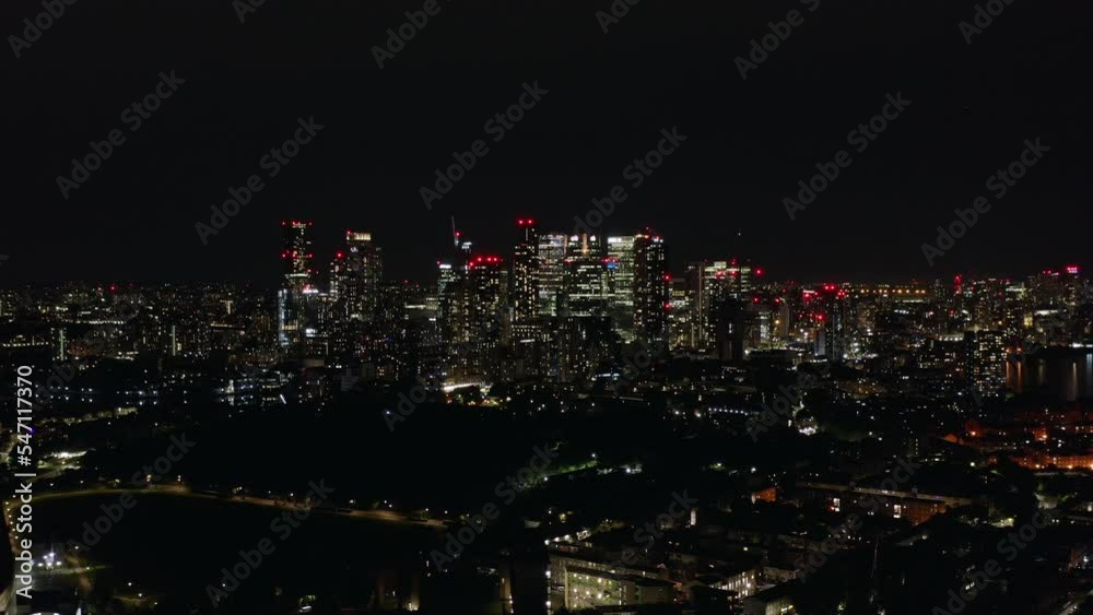 Night panoramic view of London, the largest city in England, and its financial center Canary Wharf with shining high buildings, aerial shot.