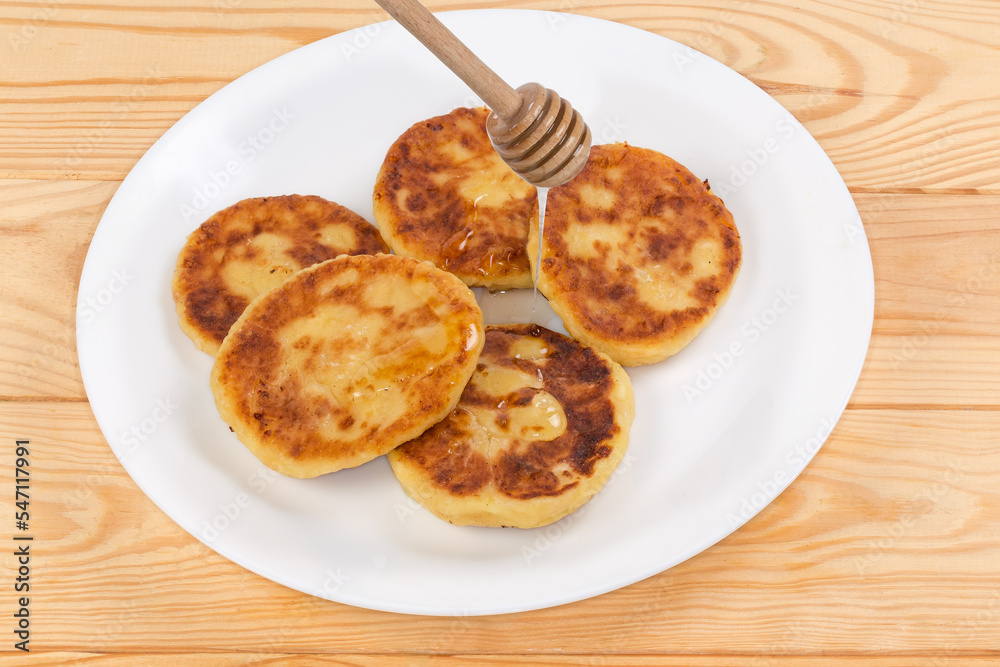 Cheese pancakes serving with honey on dish on rustic table Cheese pancakes serving with honey on dish on rustic table