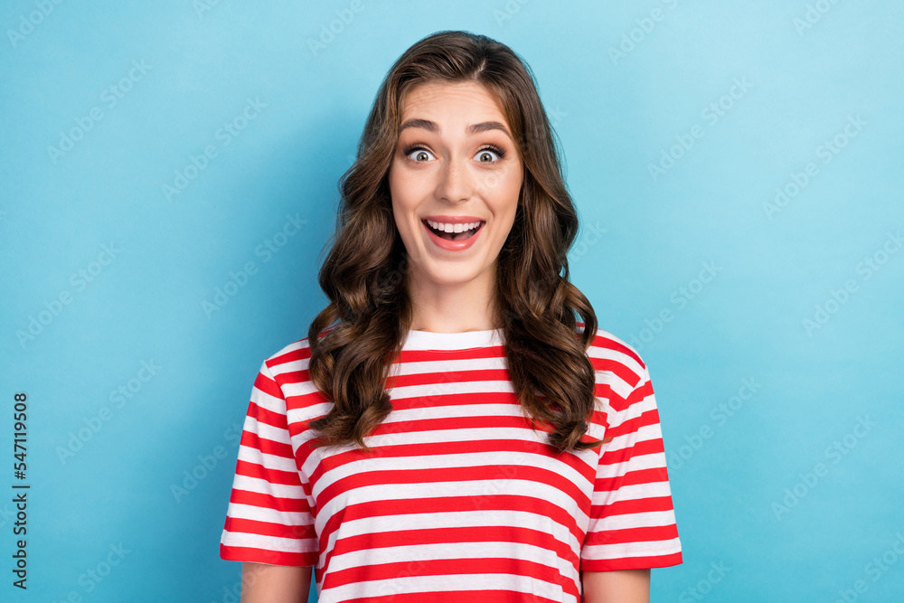 Photo of cheerful excited young lady wear striped clothes smiling open mouth isolated blue color background Photo of cheerful excited young lady wear striped clothes smiling open mouth isolated blue color background