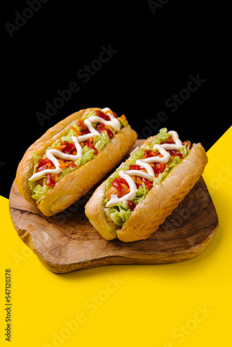Two delicious hotdogs on wooden board