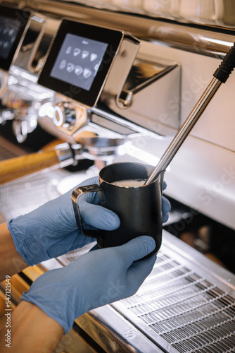 Barista making milk foam in the metal cup photo