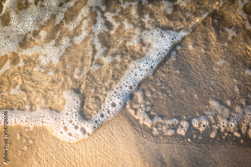 Sea water crashing on the beach seen close up