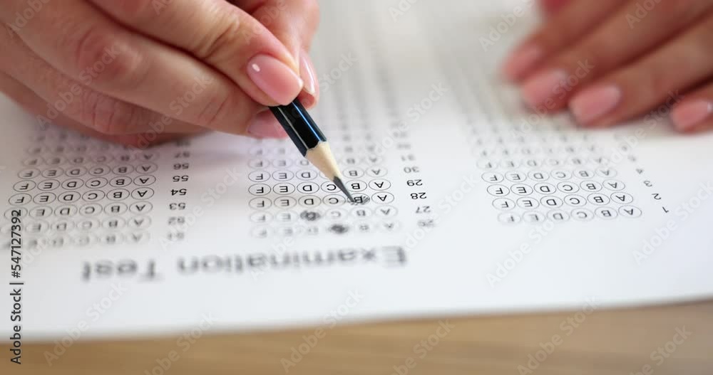 Woman hand holds pencil and marks answers to test Woman hand holds pencil and marks answers to test