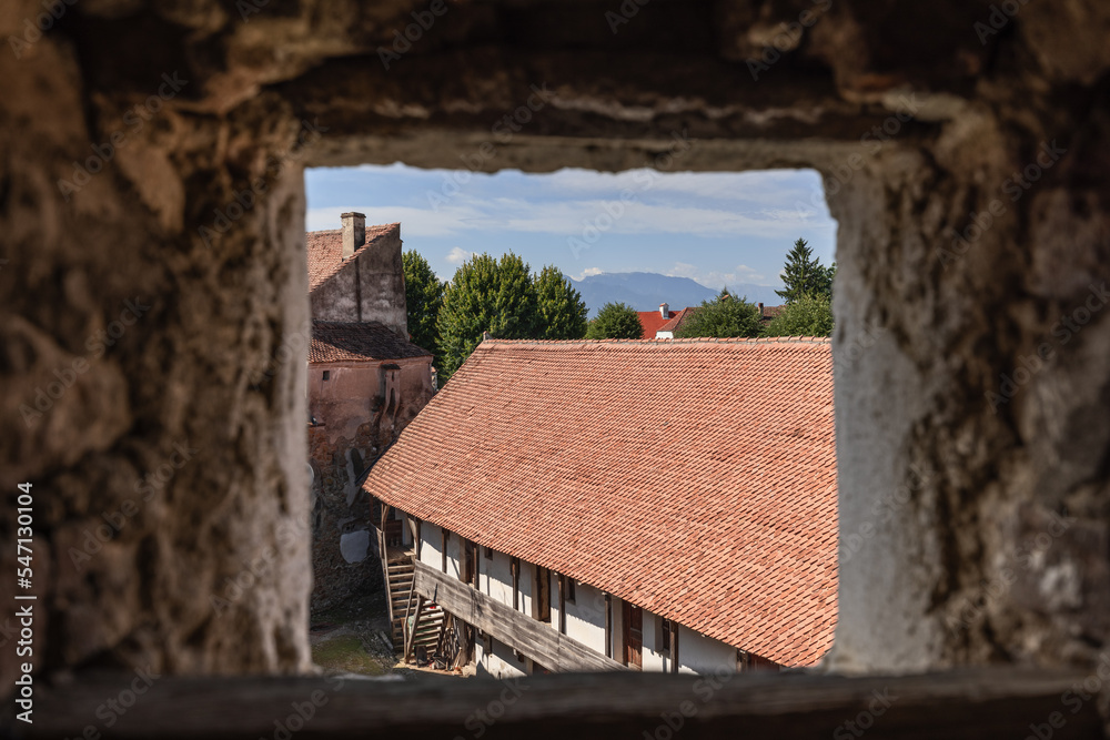 Through square loophole of Prejmer fortified church wall, Transylvanian beautiful panoramic view opens, starting from tiled fortress roof, Brasov, Romania