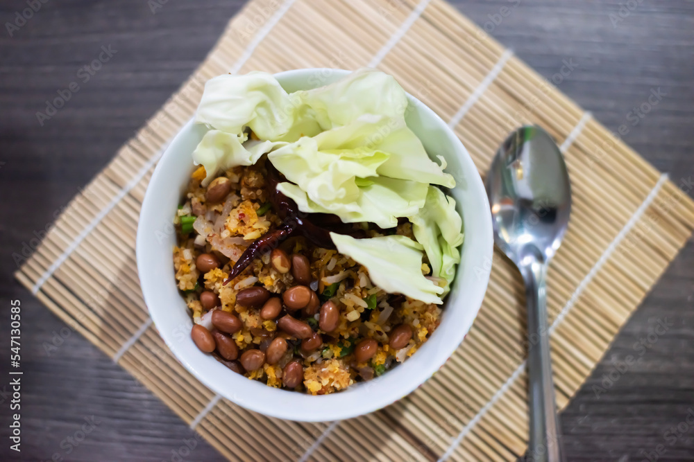 Spicy Naem Fried Rice Salad on a light brown wooden floor Placed on a dark brown table. Next to it is a spoon placed for eating, blurred Spicy Naem Fried Rice Salad on a light brown wooden floor Placed on a dark brown table. Next to it is a spoon placed for eating, blurred