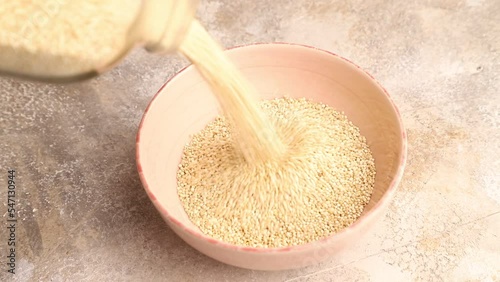quinoa pour into a ceramic bowl on a brown concrete background, side view, close up
