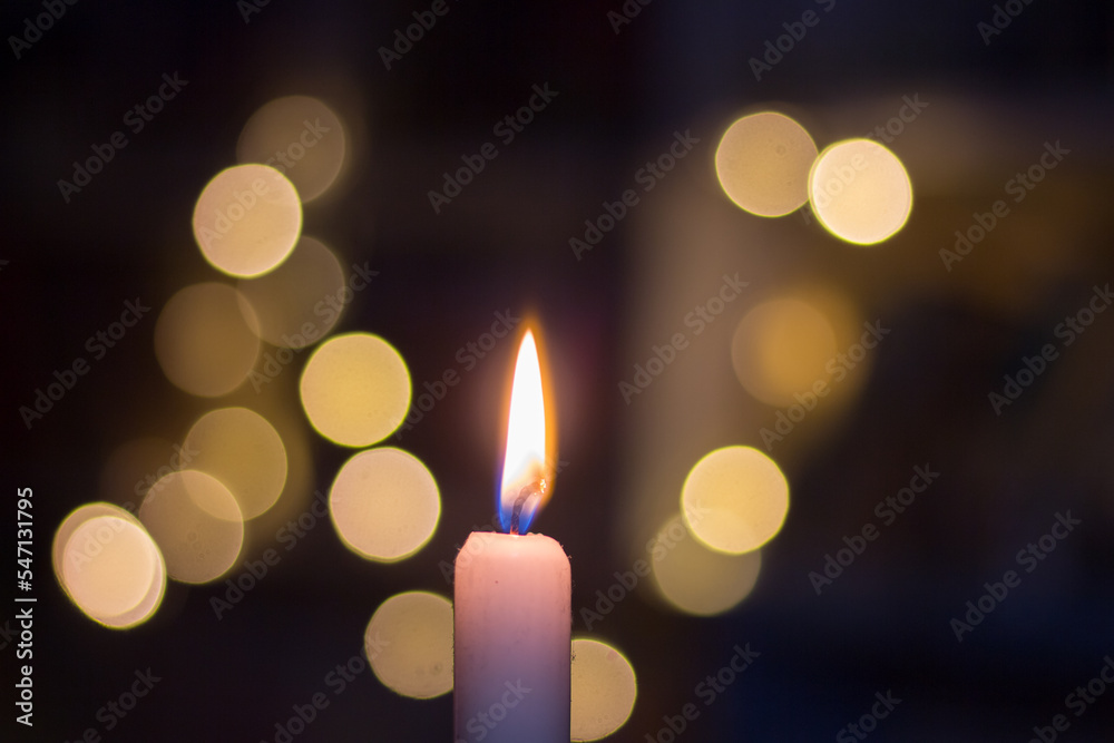 Burning candle on the background of shelves with books. Blackout in Ukraine due to war