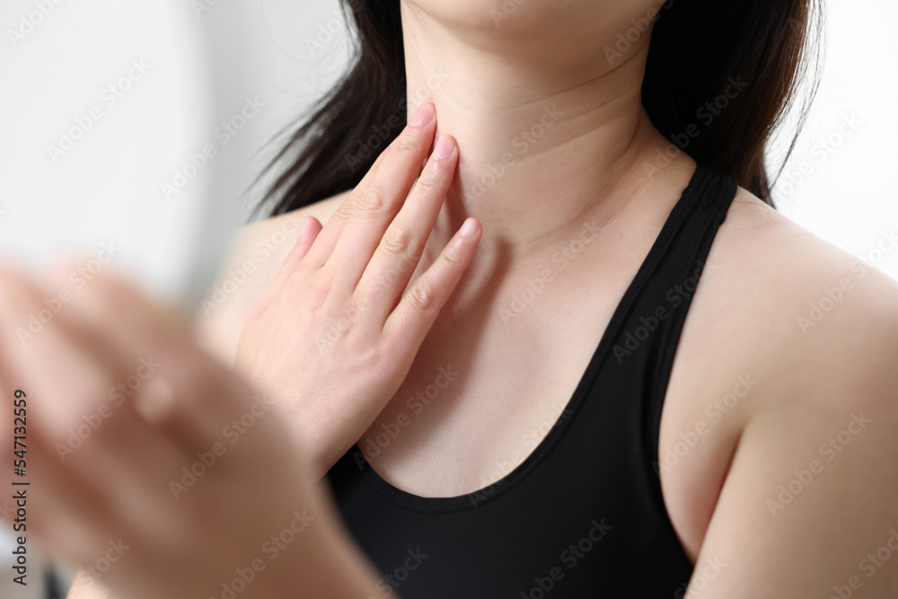 A woman looking in the mirror while touching her neck wrinkles