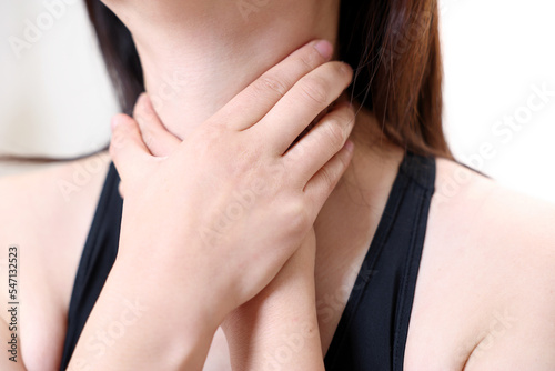 A woman suffering from esophagitis is touching her wrinkled neck. photo