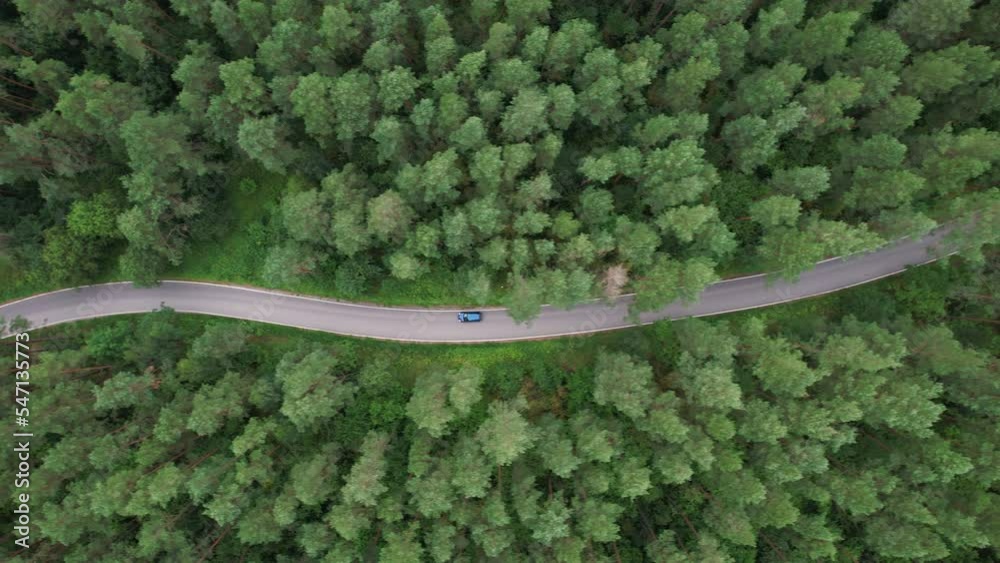 Aerial View Blue Car Driving Down an Asphalt Road Crossing Vast Forest on Summer Day. Aerial Shot of Car Driving on Road in Pine Tree Forest. Road Trip Through Forest. Scenic Summer Landscape. Aerial View Blue Car Driving Down an Asphalt Road Crossing Vast Forest on Summer Day. Aerial Shot of Car Driving on Road in Pine Tree Forest. Road Trip Through Forest. Scenic Summer Landscape.