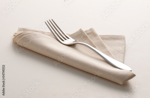 Tenedor sobre servilleta beige de hilo sobre fondo blanco. Fork on beige linen napkin on a white background.