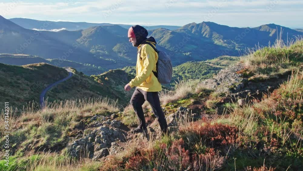 The tourist walks the mountain trail at sunrise, in the background there is a panorama of the mountain range. The tourist walks the mountain trail at sunrise, in the background there is a panorama of the mountain range.