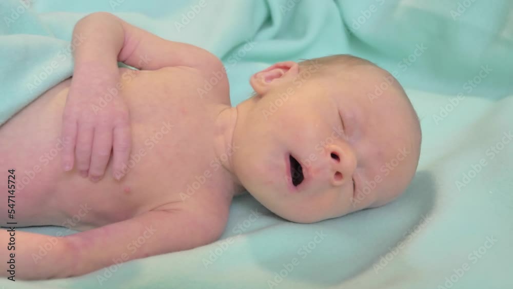 Portrait of a newborn baby. Caucasian child laying on the bed, looking around and sneezing. Slow motion shot Portrait of a newborn baby. Caucasian child laying on the bed, looking around and sneezing. Slow motion shot