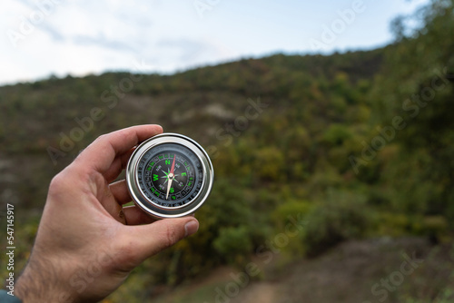 Holds a compass on the background of the forest