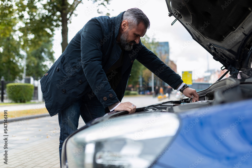 man fixing a broken car in the city man fixing a broken car in the city