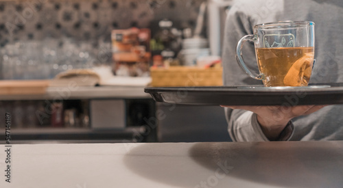 Detalle de camarero irreconocible  llevando la bandeja con el t    en la barra del restaurante.