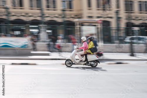 Two women driving a scooter in the city