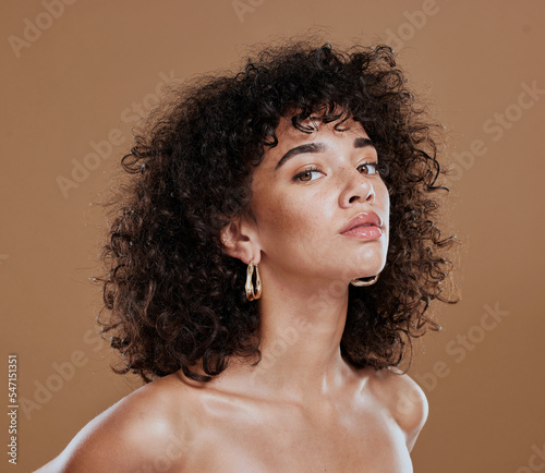 Black woman, beauty and skincare face portrait for natural afro, facial or hair care cosmetics. Healthy, beautiful and assertive model with curly hair shine and texture in brown studio background.