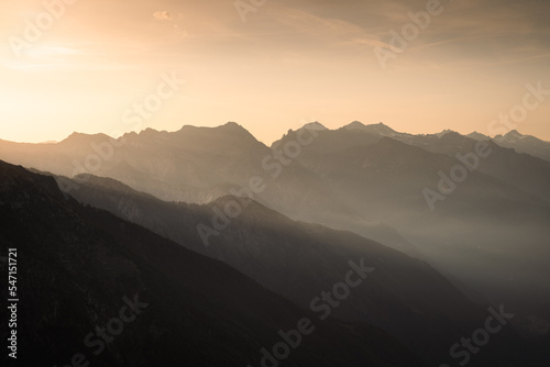 The sunset light shines behind the peaks of the Alps of Chiavenna Valley  Northern Italy