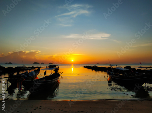 Wooden boat moored in shallow water near the beach at sunset. Romantic landscape.