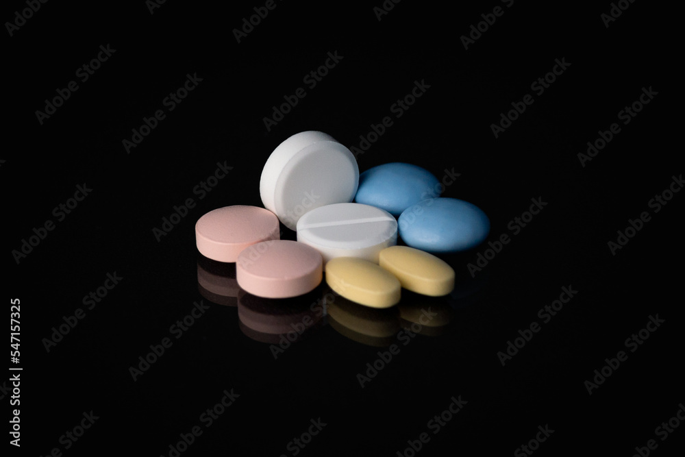 Pills and tablets on a black glass Pills and tablets on a black glass