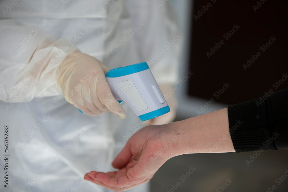 A doctor uses an outdoor thermometer gun to check body temperature for symptoms of the covid-19 virus.