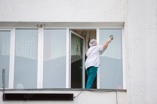 A nurse in a hospital or clinic washes windows. A cleaner in a medical facility.