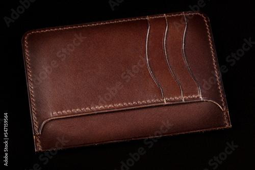 Brown leather wallet on a dark background.