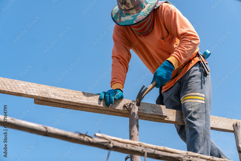 Worker use hammer hit nails on scaffolding for support second floor. Worker use hammer hit nails on scaffolding for support second floor.