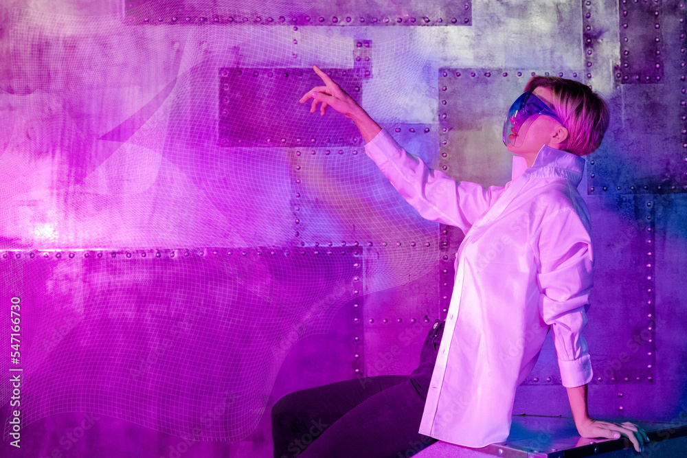 Beauty woman in modern VR glasses with outstretched hand on neon blue pink metal background. Technologies of future. High quality photo Beauty woman in modern VR glasses with outstretched hand on neon blue pink metal background. Technologies of future. High quality photo