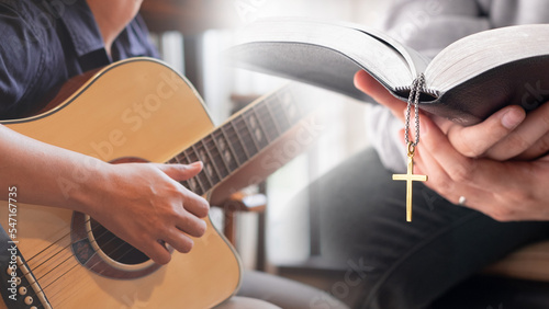 Musician is sitting and playing an acoustic guitar and Christian praying, reading bible in his or her hands. Concept of woship and church service presentation background photo
