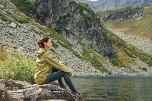 Woman solo traveler looks at the beautiful view of mountain lake