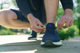 Closeup of young man runner tying her shoelaces. Selective focus